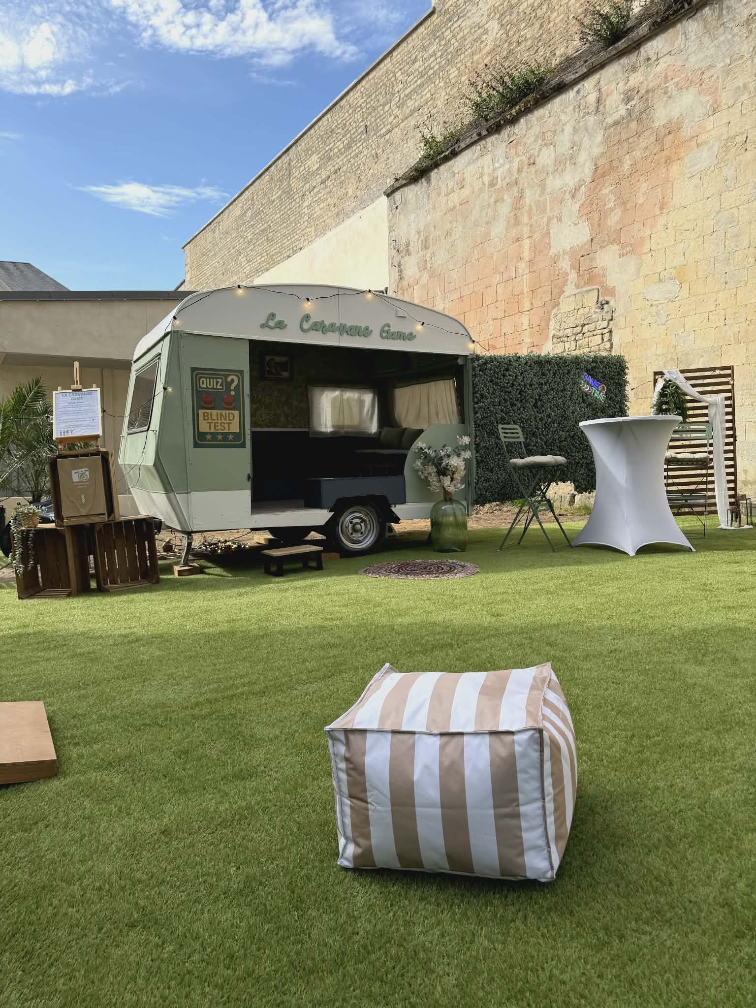 La Caravane Game installée en extérieur pour un événement : caravane vintage de quiz et blind test avec néon Game Time, à Caen en Normandie