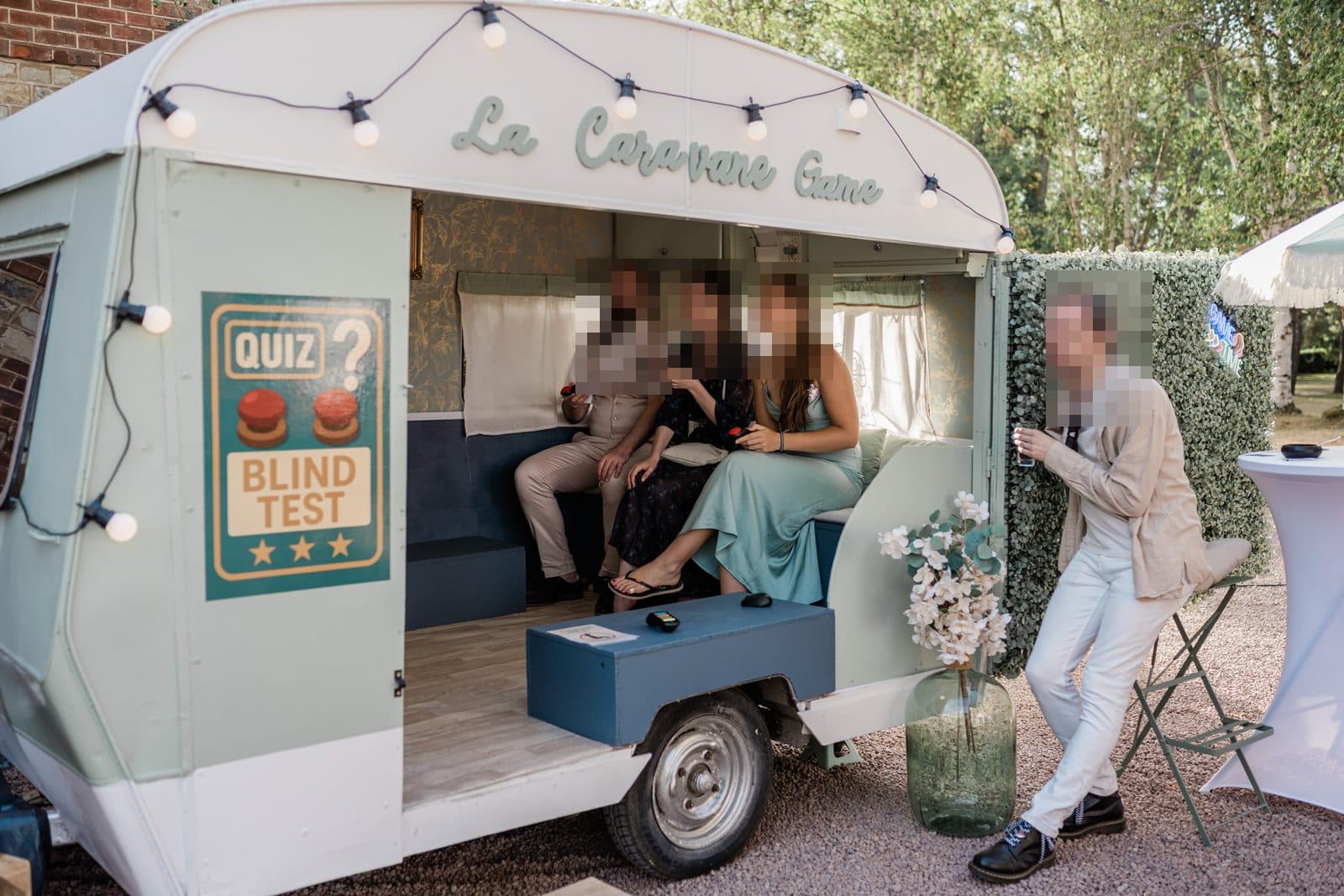 Des invités jouent au quiz et au blind test, buzzers en main, dans la caravane Suzanne lors d’un mariage en Normandie