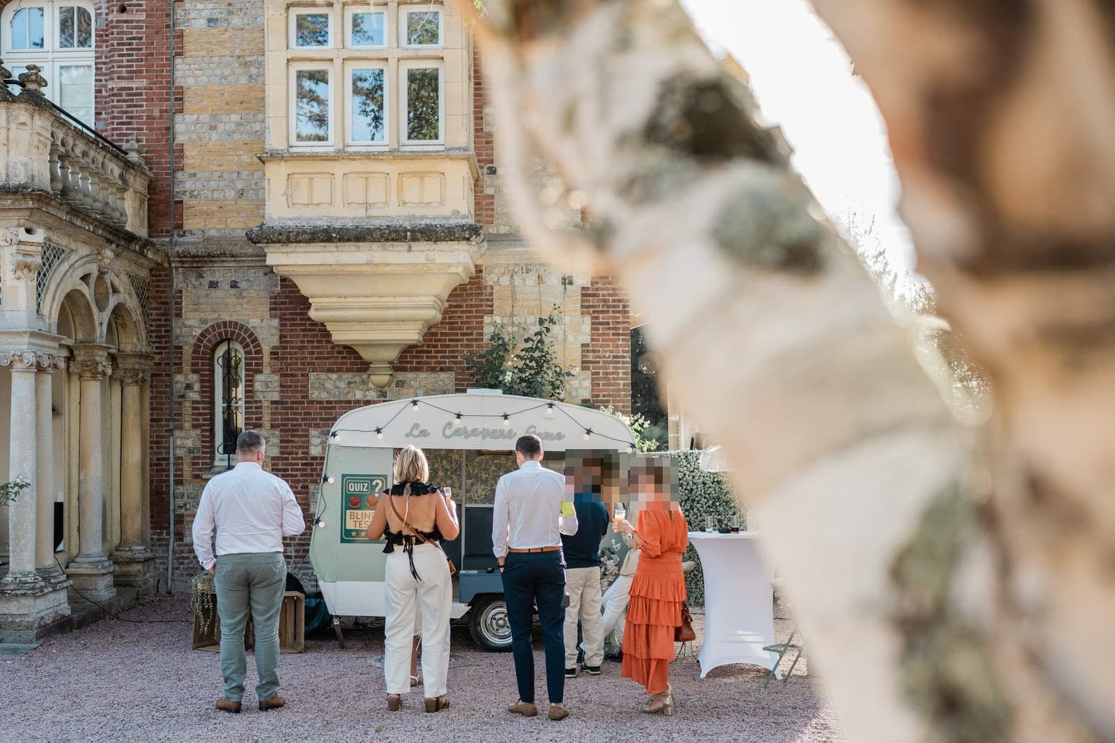 La caravane Suzanne installée lors d’un mariage dans un château en Normandie, invités réunis autour pour le quiz et le blind test
